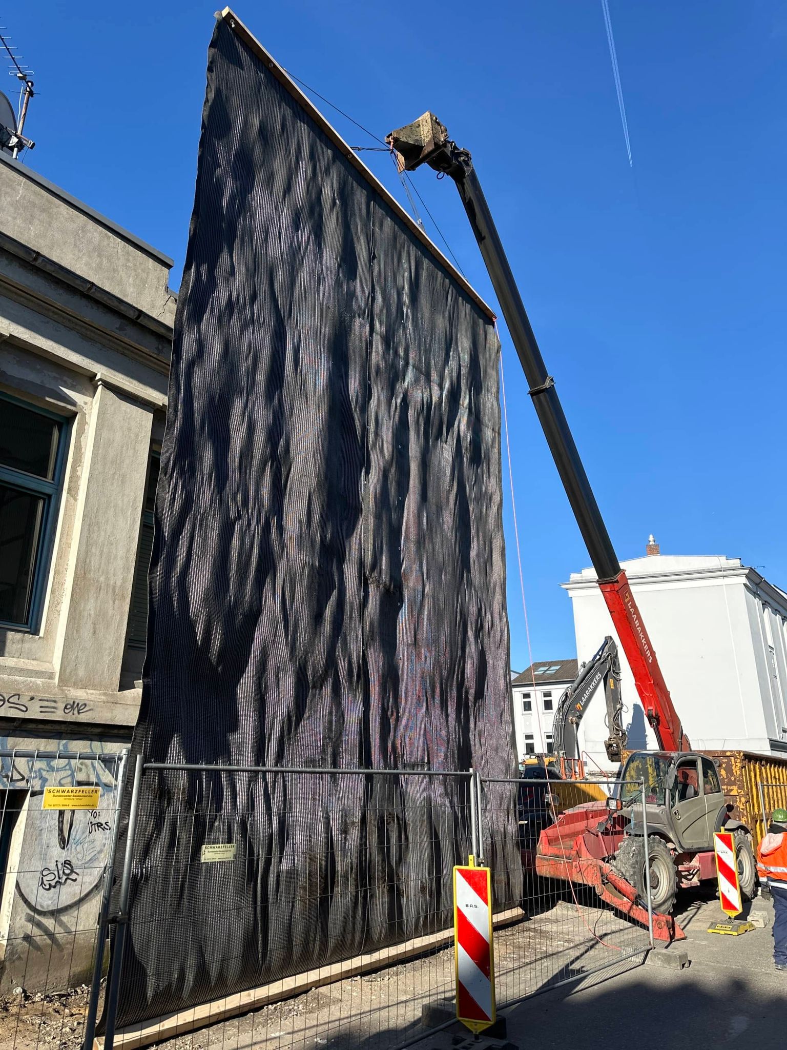 · A black vertical containment curtain installed along the facade